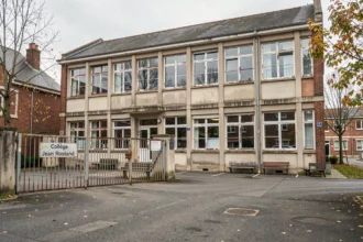 Façade extérieure d'un collège Jean Rostand avec cour et grille d'entrée typique d'un établissement scolaire français