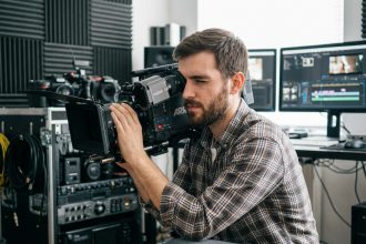 Jeune homme sérieux utilisant une caméra en studio moderne