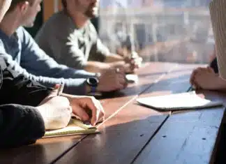 Comment développer des compétences en leadership people sitting on chair in front of table while holding pens during daytime